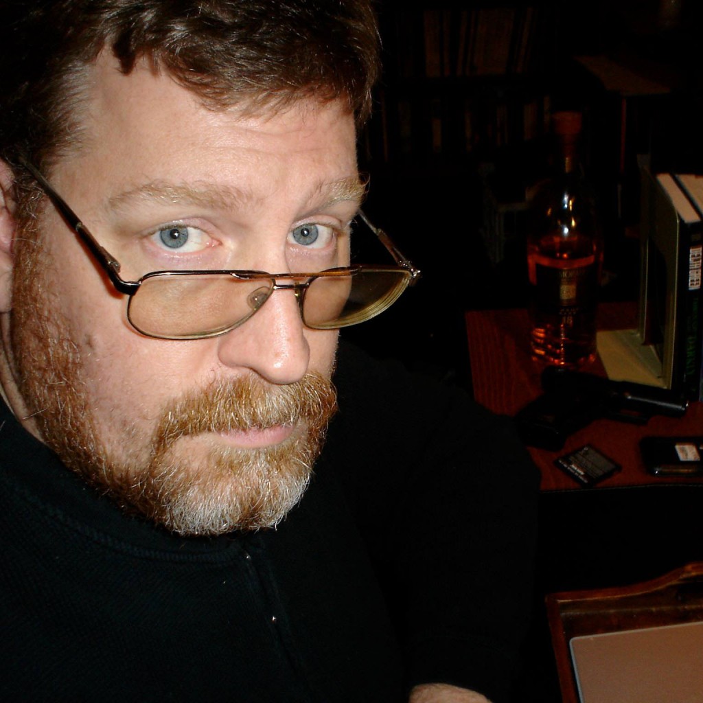 Image is Adam Scott Glancy, a bearded middle aged caucasian man wearing glasses.